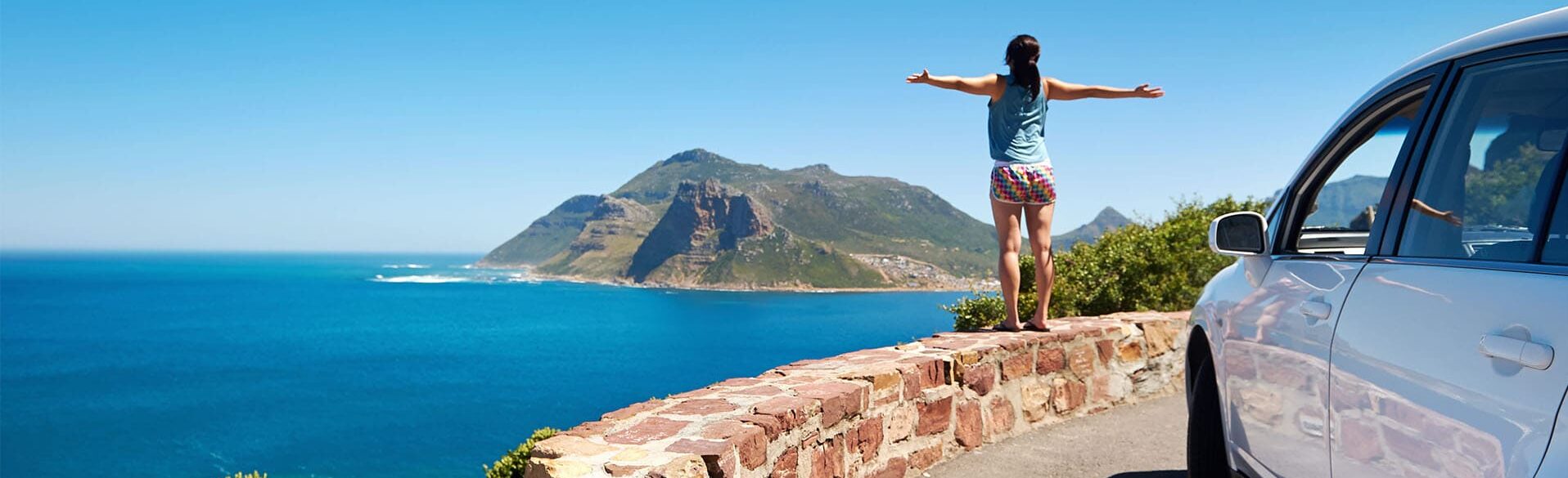 Frau auf einer Mauer mit Insel im Hintergrund
